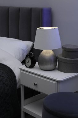 İçinde lamba, çalar saat ve yatağın yanındaki dekorun bulunduğu komodin.
