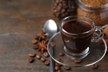 Bir fincan aromatik kahve, fasulye, hazır toz ve baharatlar ahşap masada, yakın plan. Metin için boşluk