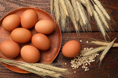 Çiğ yumurta ve buğday dalları tahta masada, düz yerde.