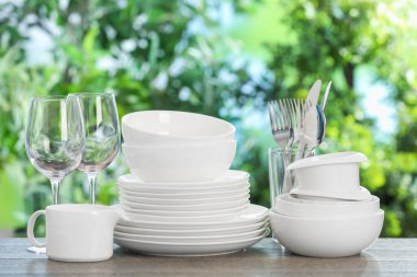 Ahşap masada, bulanık yeşil arka planda farklı temiz tabaklar.