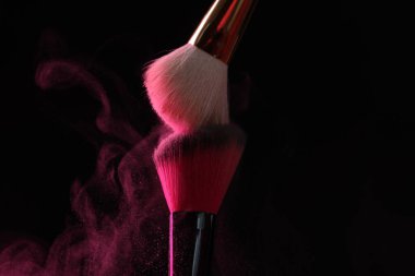 Siyah arka planda pembe göz farlı makyaj fırçaları, yakın plan