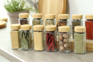 Kapalı alanda, ahşap masadaki kavanozlardaki farklı aromatik baharatlar.