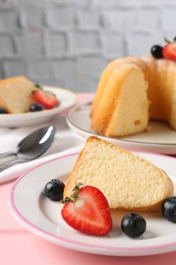 Pembe ahşap masada meyveli kek parçaları, yakın plan.