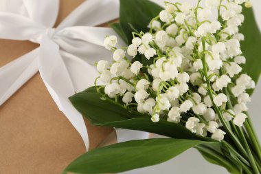 Vadi çiçeklerinin güzel zambakları ve beyaz masada hediye, yakın plan.