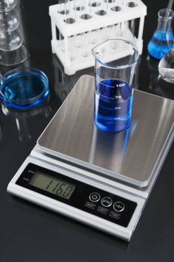 Siyah ayna masasındaki deney tüpü ve diğer laboratuvar camlarıyla ölçeklendir, yakın plan.