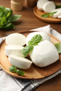 Nefis mozzarella peyniri parçaları ve fesleğen yaprakları ahşap masada, yakın plan.