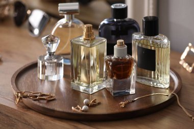 Farklı parfüm şişeleri ve aksesuarlar ahşap masada, yakın plan.