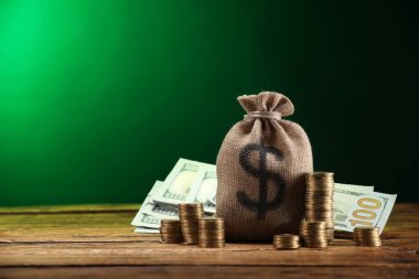 Çanta, dolar banknotları ve ahşap masaya istiflenmiş paralar yeşil eğimli arkaplan, metin için boşluk