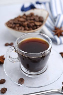 Bir fincan aromatik kahve, fasulye ve yıldız anason beyaz masada, yakın plan.