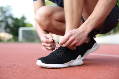 Stadyumda ayakkabı bağcığı bağlayan adam, yakın plan. Metin için boşluk