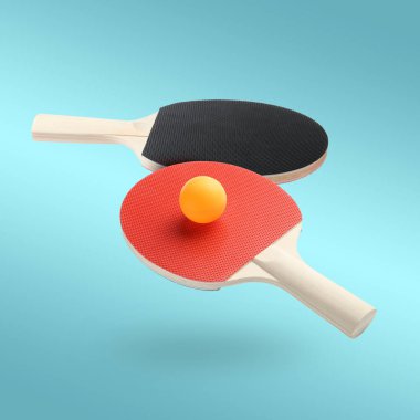 Masa tenisi raketleri ve top açık mavi arka planda.