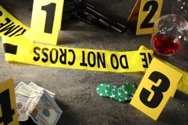 Adli tıp uzmanı. Sarı olay yeri bandı, işaretler ve kanıtlar gri masada, yakın plan.