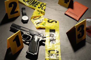 Adli tıp uzmanlığı. Gri arka planda delil, işaret ve polis bandı olan olay yeri, yakın plan.