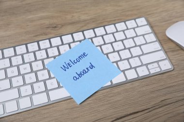 Sözcüklü yapışkan not Gemiye hoş geldiniz, bilgisayar klavyesi ve fare ahşap masa, yakın plan