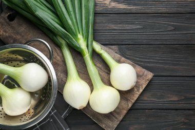 Taze taze taze soğanlar, siyah ahşap masa üzerinde kesme tahtasıyla, düz bir şekilde. Metin için boşluk