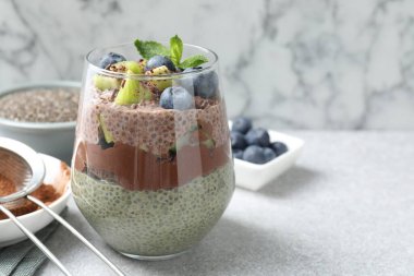 Chia tohumlu çikolatalı puding, kivi, nane ve böğürtlenli cam, gri desenli masada mermer arka planda, yakın plan. Metin için boşluk