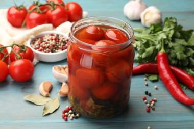 Kavanozda domates turşusu ve açık mavi ahşap masada malzemeler, yakın plan.