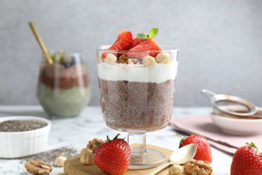 Chia tohumlu çikolatalı puding, çilek, yoğurt ve fındıklar beyaz mermer masada, yakın plan.