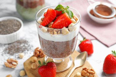 Chia tohumlu çikolatalı puding, çilek, yoğurt ve fındıklar beyaz mermer masada, yakın plan.