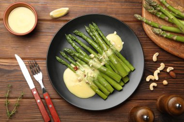 Ahşap masada sosla servis edilen lezzetli pişmiş kuşkonmaz.