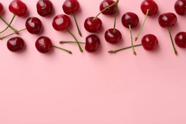 Pembe arka planda taze kirazlar, düz uzanmış. Metin için boşluk