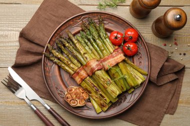 Lezzetli pişmiş kuşkonmaz, domuz pastırması ve baharatla servis edilir.