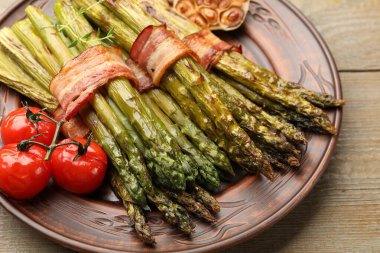 Ahşap masada domuz pastırması ile servis edilen lezzetli kuşkonmaz, yakın plan.