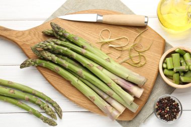 Taze çiğ kuşkonmaz mızraklar, beyaz ahşap masa üzerinde bıçak ve yağ.