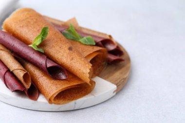 Lezzetli meyve dürümleri ve nane şekeri ışık masasında, yakın plan. Metin için boşluk