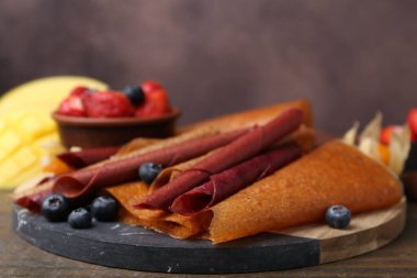 Lezzetli meyve dürümleri ve böğürtlenler ahşap masada, yakın plan.