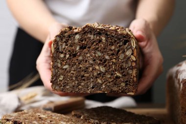 Taze pişmiş ekmeği olan kadın gri arka planda, yakın plan.