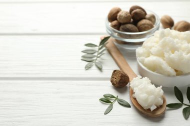 Doğal Shea yağı, fındık ve yapraklar beyaz ahşap masada, yakın plan. Metin için boşluk