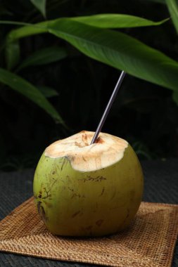 Yeşil hindistan cevizi, ferahlatıcı içecek ve hasır hasır masa üzerinde saman, yakın plan.