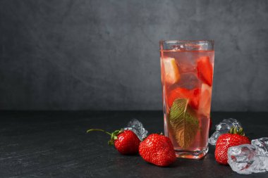 Çilekli içecek ve koyu dokulu masa üzerindeki buz gri arka planda, yakın plan. Metin için boşluk