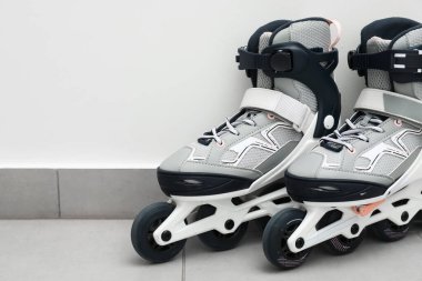 Beyaz duvarın yanında bir çift paten, yakın plan. Metin için boşluk