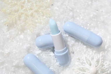 Nemlendirici dudak kremleri ve yapay karla süslenmiş Noel süsü. Kış bakımı