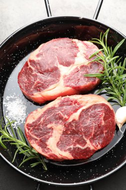 Gri masadaki fırında pişirme kabında çiğ et ve baharat parçaları.