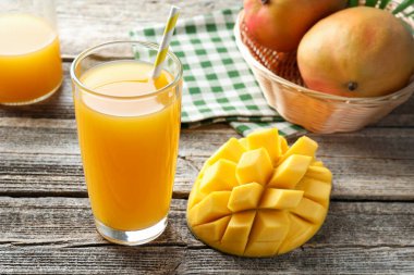 Bardakta lezzetli mango suyu ve ahşap masada taze meyve, yakın plan.