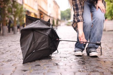 Islak kaldırımda şemsiyesi kırık bir kadın, yakın plan.