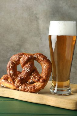 Lezzetli krakerler ve yeşil ahşap masada bir bardak bira. Gri desenli arka plan, yakın plan.