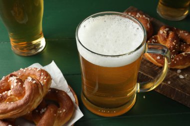 Lezzetli krakerler ve biralar yeşil ahşap masada, yakın plan.