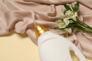 Bej arka planda kumaş yumuşatıcı, çiçekler ve renk bezi, üst görünümde.