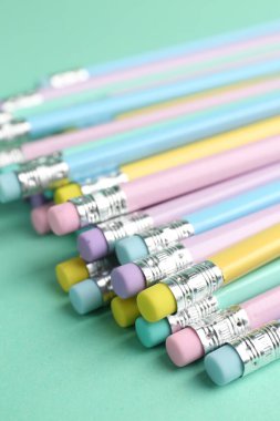 Turkuaz arka planda silgisi olan birçok grafit kalem, yakın plan