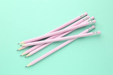 Turkuaz arka planda silgileri olan birçok grafit kalem, düz konum