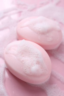 Pembe arka planda köpüklü sabun çubukları, yakın plan.