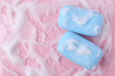 Pembe arka planda köpüklü sabun kalıpları, düz yatış. Metin için boşluk