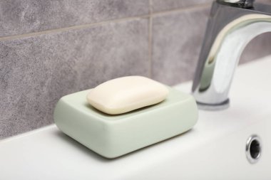 Musluğun yanındaki sabun barı banyoda lavabonun üstünde, yakın plan.