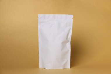 Açık turuncu arka planda fermuarlı bir stand-up kesesi. Tasarım için model