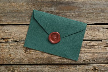 Ahşap masa üzerinde balmumu mühürü olan güzel bir davetiye zarfı.