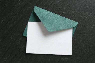 Boş davetiye kartı ve zarf siyah masanın üstünde, en üstte. Tasarım için boşluk